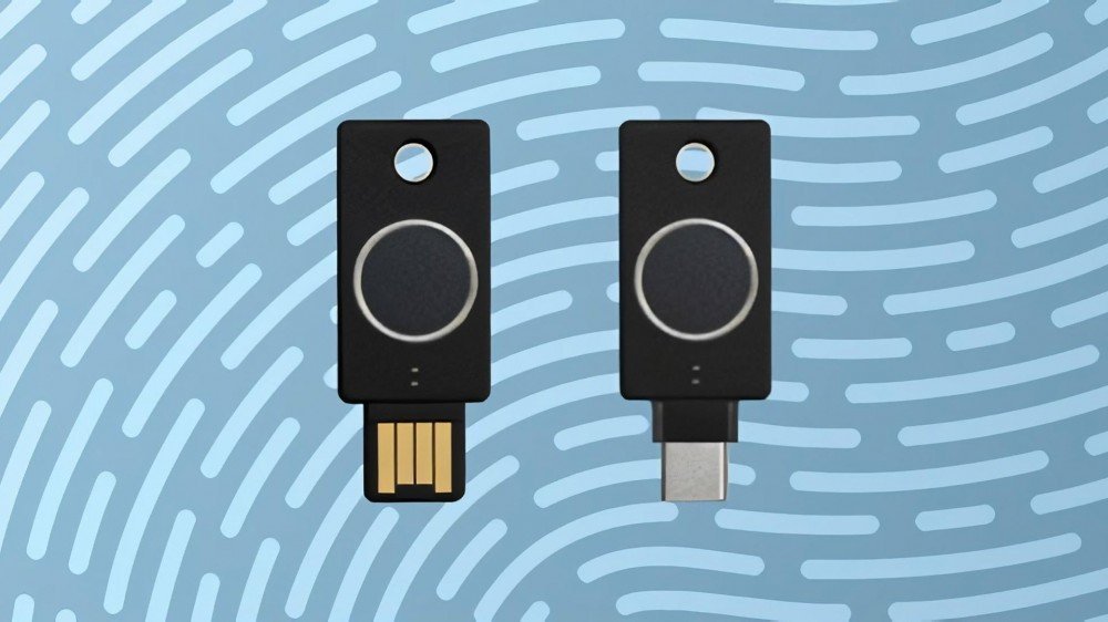 Deux Yubikeys, l'un en USB-A l'autre en USB-C, avec des capteurs d'empreintes digitales, posés sur un fond à motifs d'empreintes digitales.