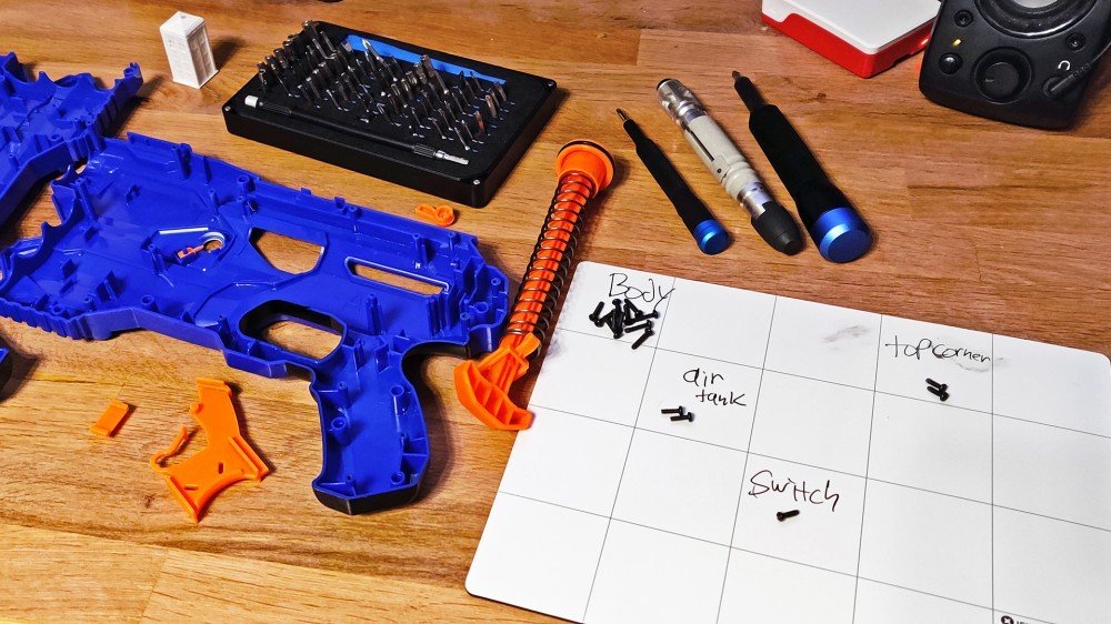 Deux kits iFixit entourés d'un pistolet Nerf déchiré.