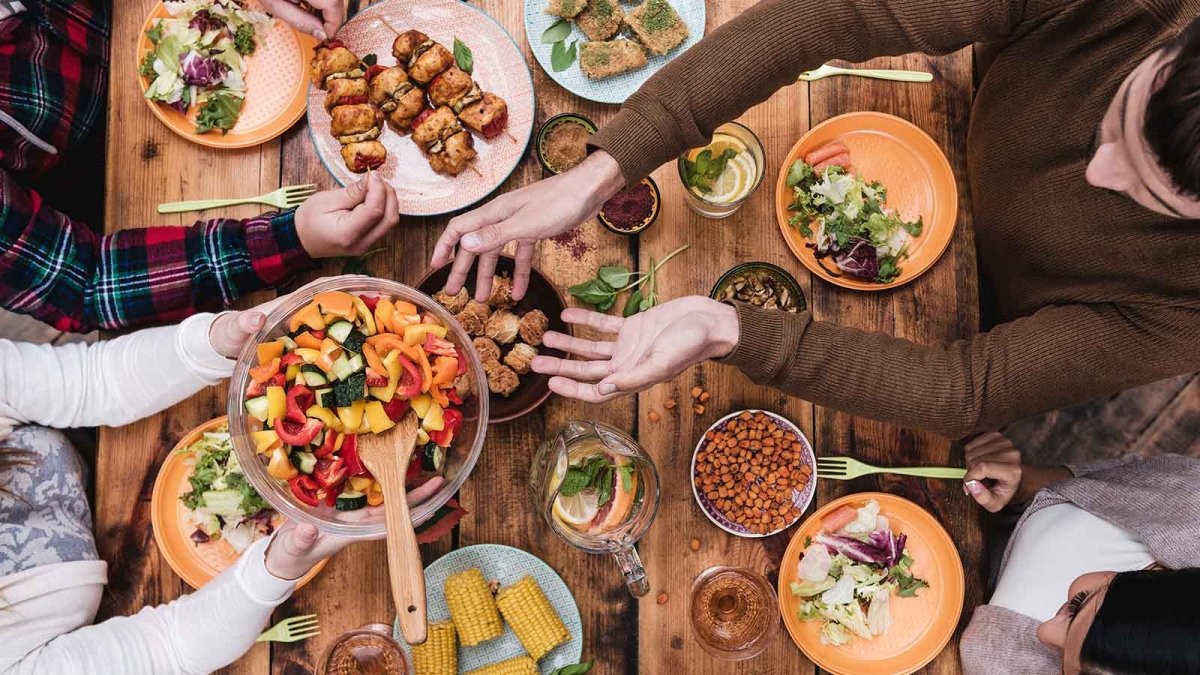 Amis partageant un repas avec de nombreuses options végétariennes sur la table.