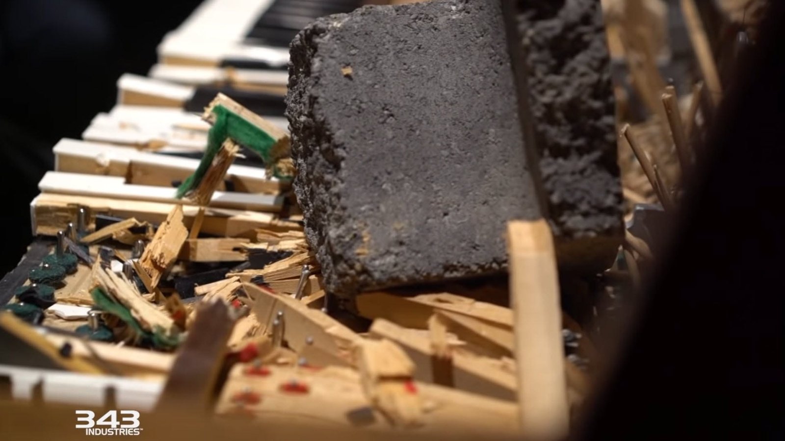 Un clavier de piano cassé, avec un rocher géant posé sur les touches détruites.