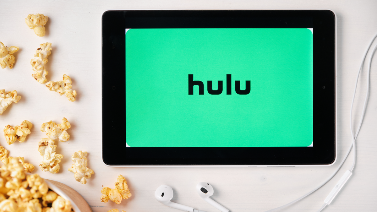 Logo Hulu sur l'écran de la tablette posée sur la table blanche et saupoudré de maïs soufflé dessus