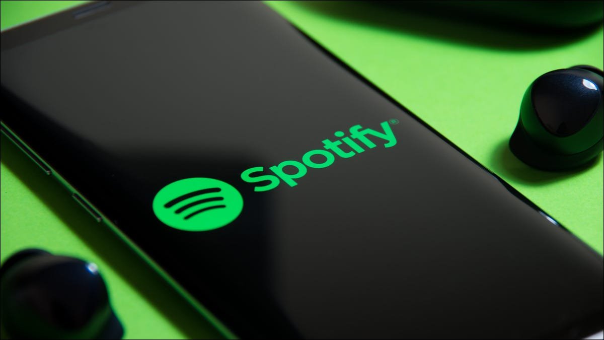 Logo Spotify sur un smartphone à côté d'écouteurs véritablement sans fil