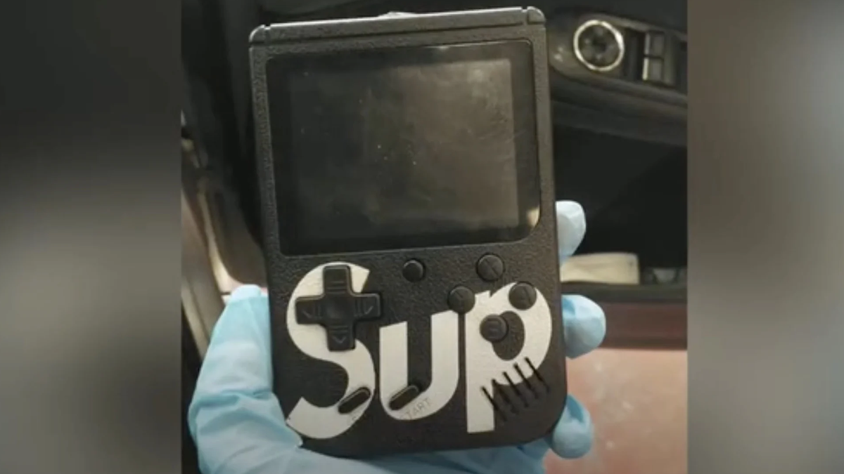 La fausse Game Boy est noire et a un "SUPRÊME" décalque.
