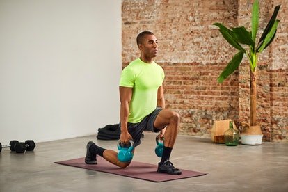 Un homme faisant des mouvements brusques à la maison tout en tenant des kettlebells.