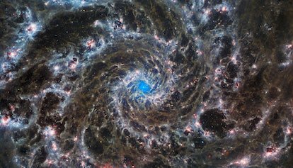 De délicats filaments gris et tissés forment un motif en spirale qui s'enroule vers l'extérieur depuis le centre de la galaxie...