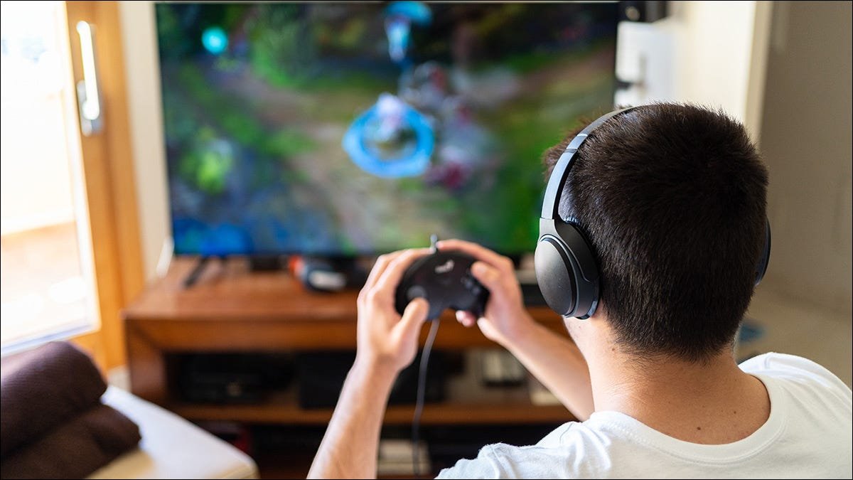 Quelqu'un joue à un jeu vidéo tout en portant des écouteurs sans fil.