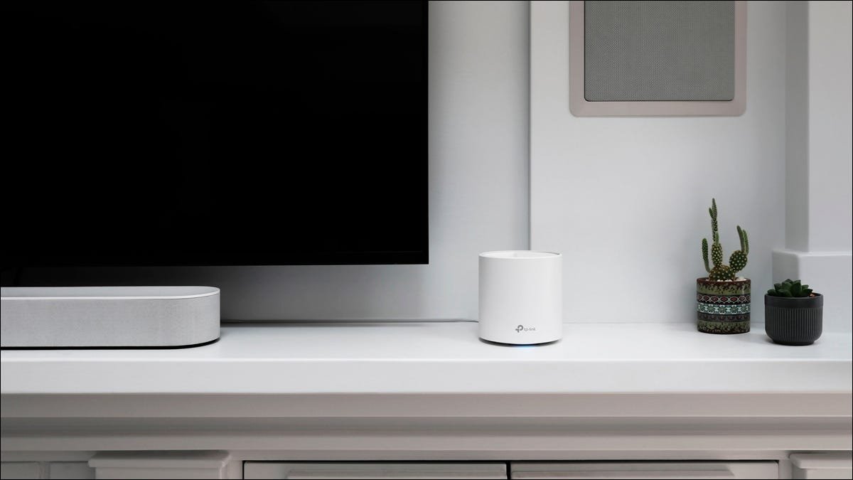 Un routeur maillé TP-Link moderne, assis sur une console TV.