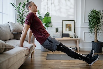 L'homme fait des triceps à la maison en utilisant un canapé.