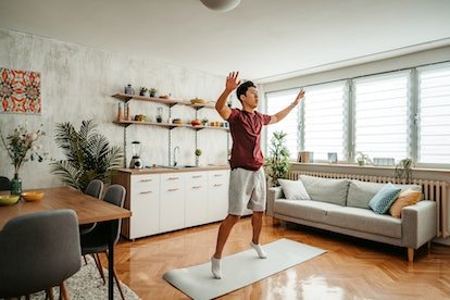 Un homme faisant des sauts avec écart à la maison.