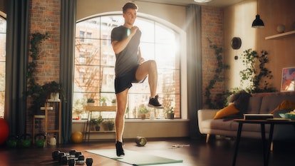 Un homme fait de l'exercice à genoux à la maison sur un tapis de yoga.