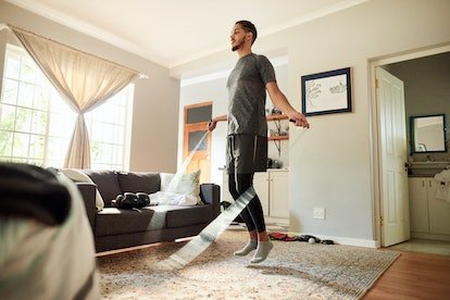 Homme sautant à la corde dans son salon lors d'une séance d'entraînement à domicile.