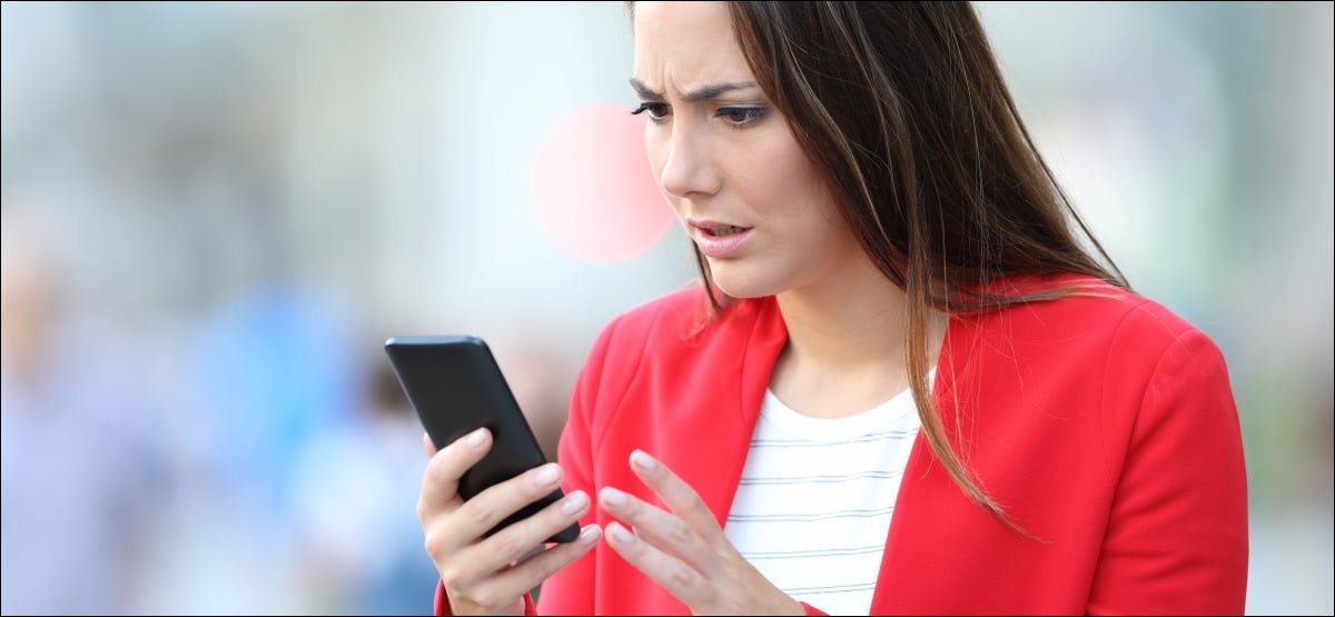 Une femme inquiète regarde son smartphone.