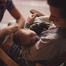 Femme tenant bébé avec partenaire à proximité.