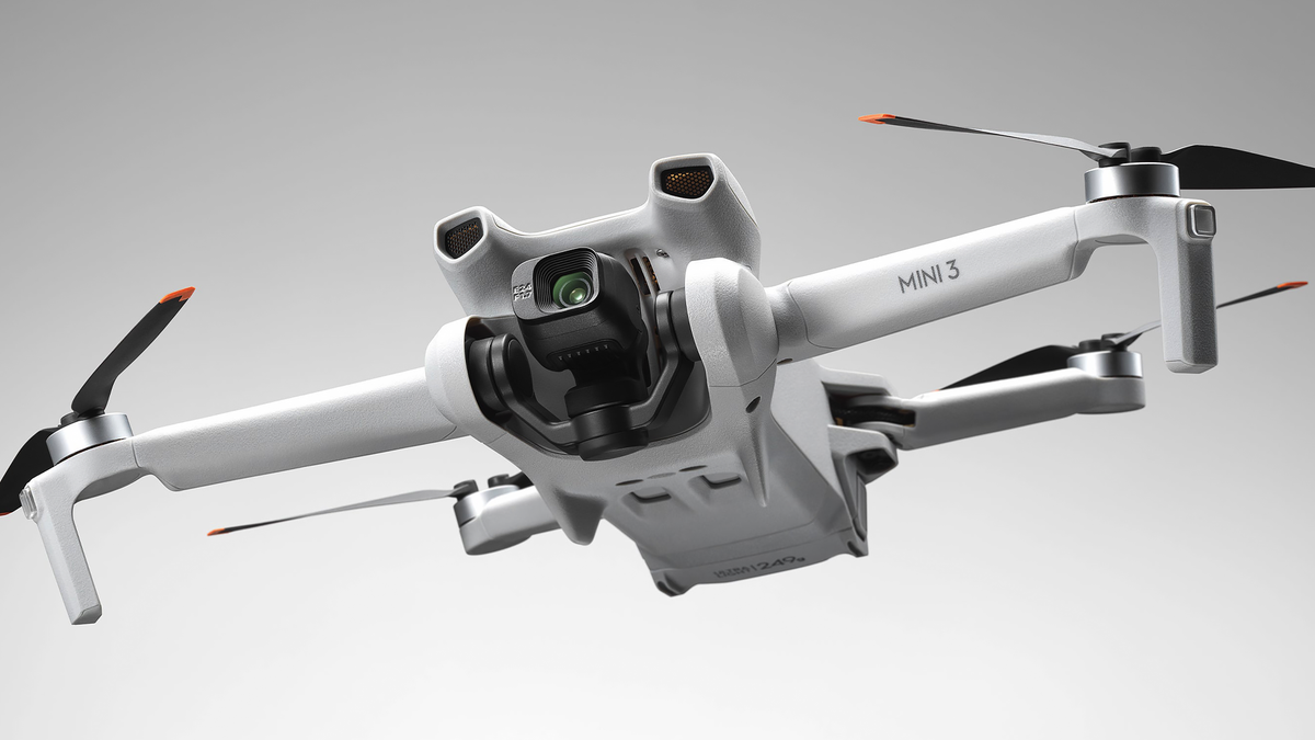 Le DJI Mini 3 volant sur fond gris.