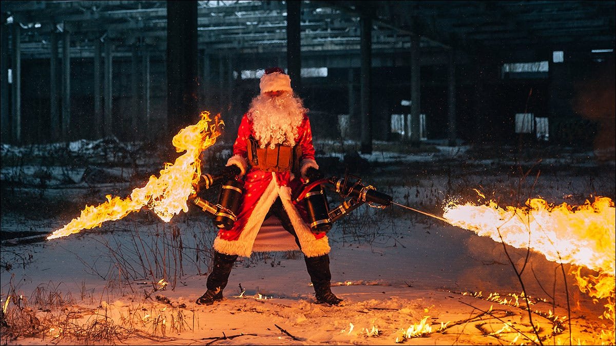 Père Noël, lance-flammes à double maniement, font fondre la neige à l'ombre d'un grand entrepôt.