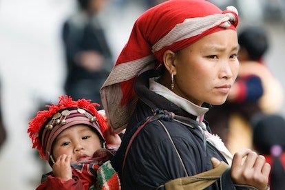 Femme Dzao rouge avec bébé sur le dos dans la tribu des collines de sling Sapa Vietnam.  (Photo par : Andrew Woodley/Éducation...