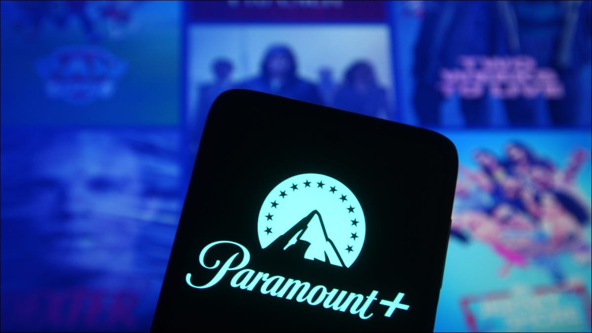 Logo Paramount+ sur un smartphone devant plusieurs affiches médiatiques