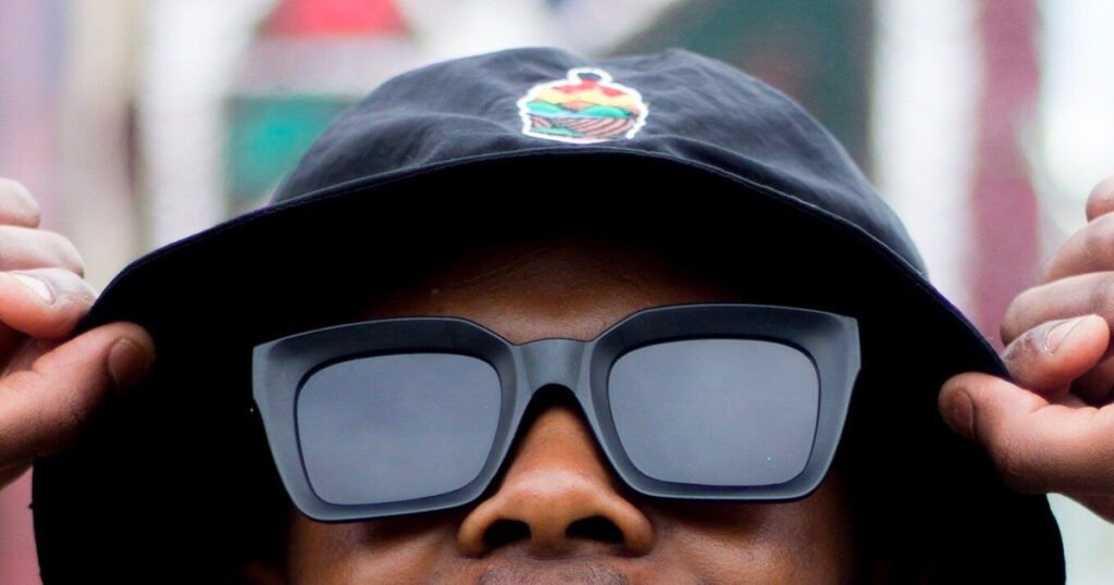 homme portant un chapeau de seau noir et des lunettes de soleil noires