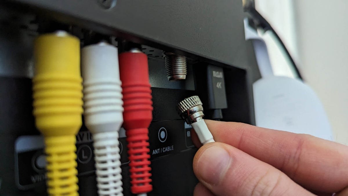 Personne branchant une antenne TV intérieure sur un téléviseur