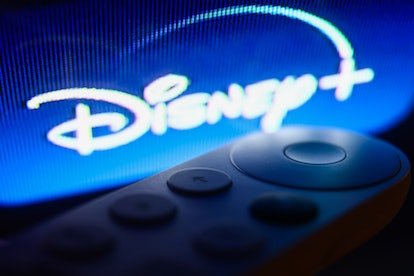 Le logo Disney + sur le menu Chromecast affiché sur un écran de télévision et la télécommande Chromecast sont visibles dans t ...