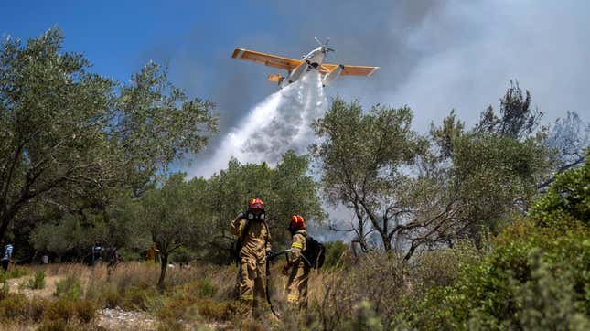 Un avion largue de l'eau alors que les pompiers opèrent lors d'un incendie de forêt dans le village de Vati, sur l'île de Rhodes, dans la mer Égée, au sud-est de la Grèce, le 25 juillet 2023.