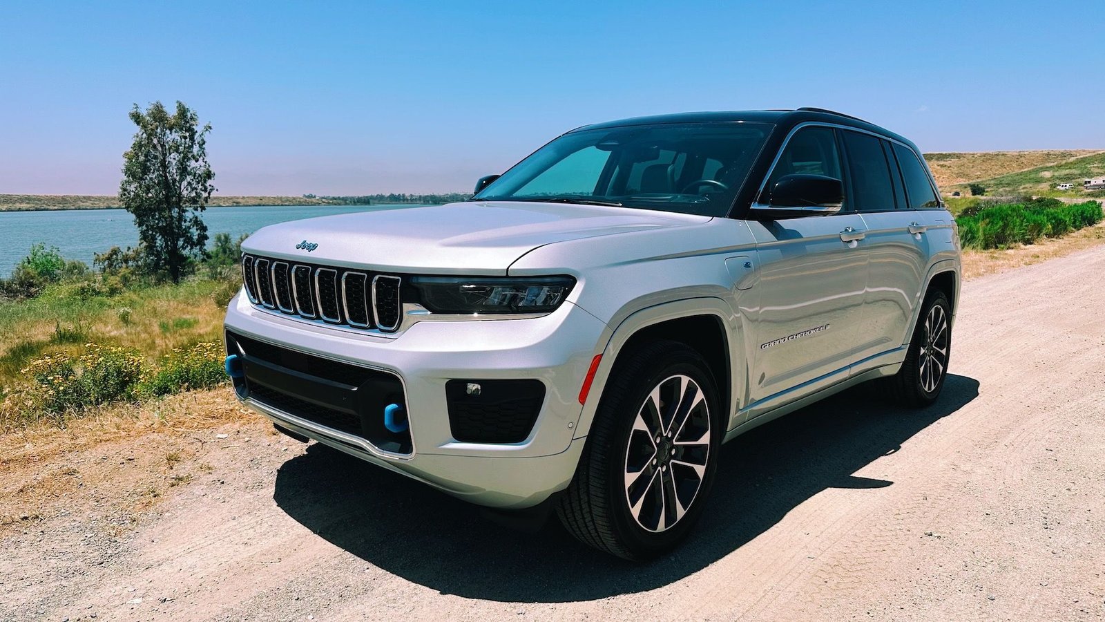 Une vue de face du Jeep Grand Cherokee Overland 4xe de couleur argent devant un lac
