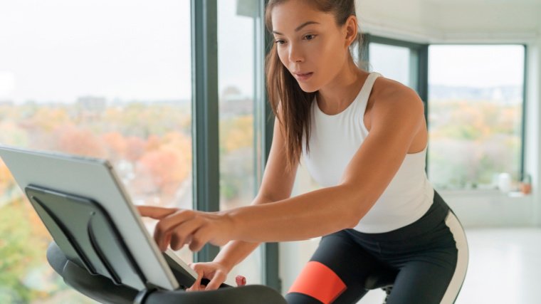 Personne aux cheveux longs dans une salle de sport utilisant un vélo stationnaire