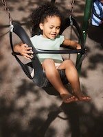 Une fille souriante se balance sur une aire de jeux.