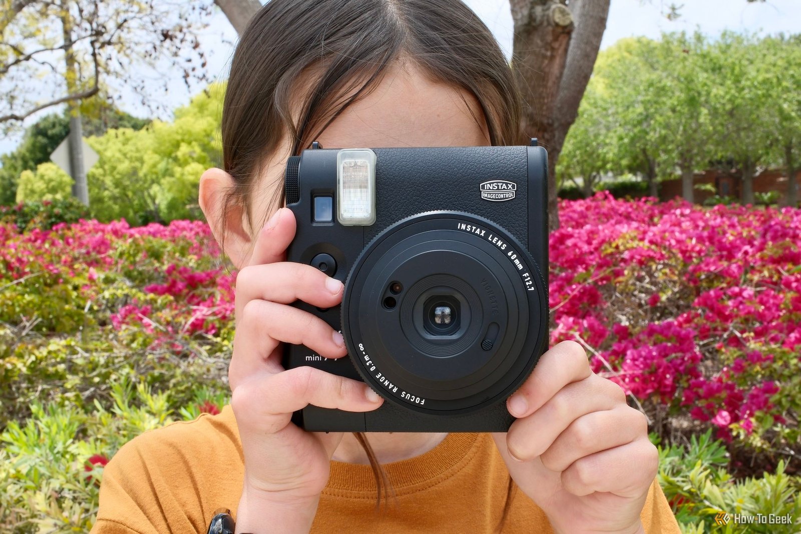 Une fille tenant le Fujifilm Instax Mini 99 sur le point de prendre une photo