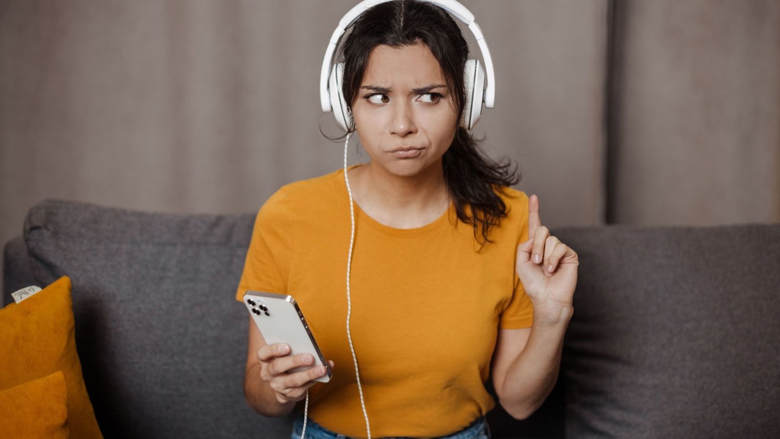 Une femme écoute son iPhone avec des écouteurs et a l'air malheureuse.