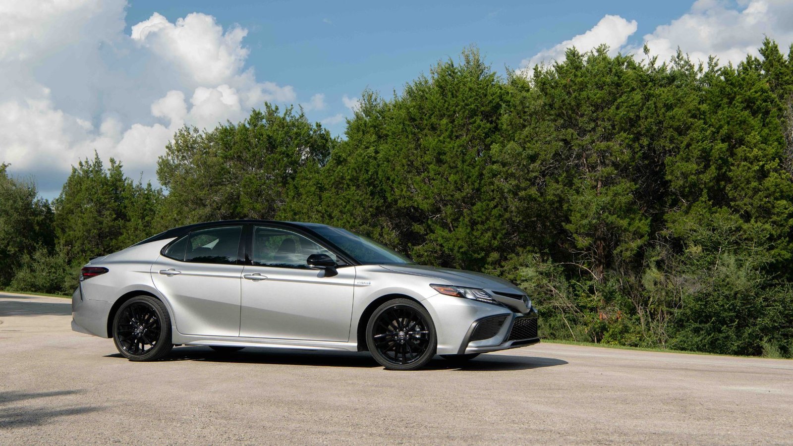 Silver 2022 Toyota Camry garé sur le tarmac avec des arbres en arrière-plan.