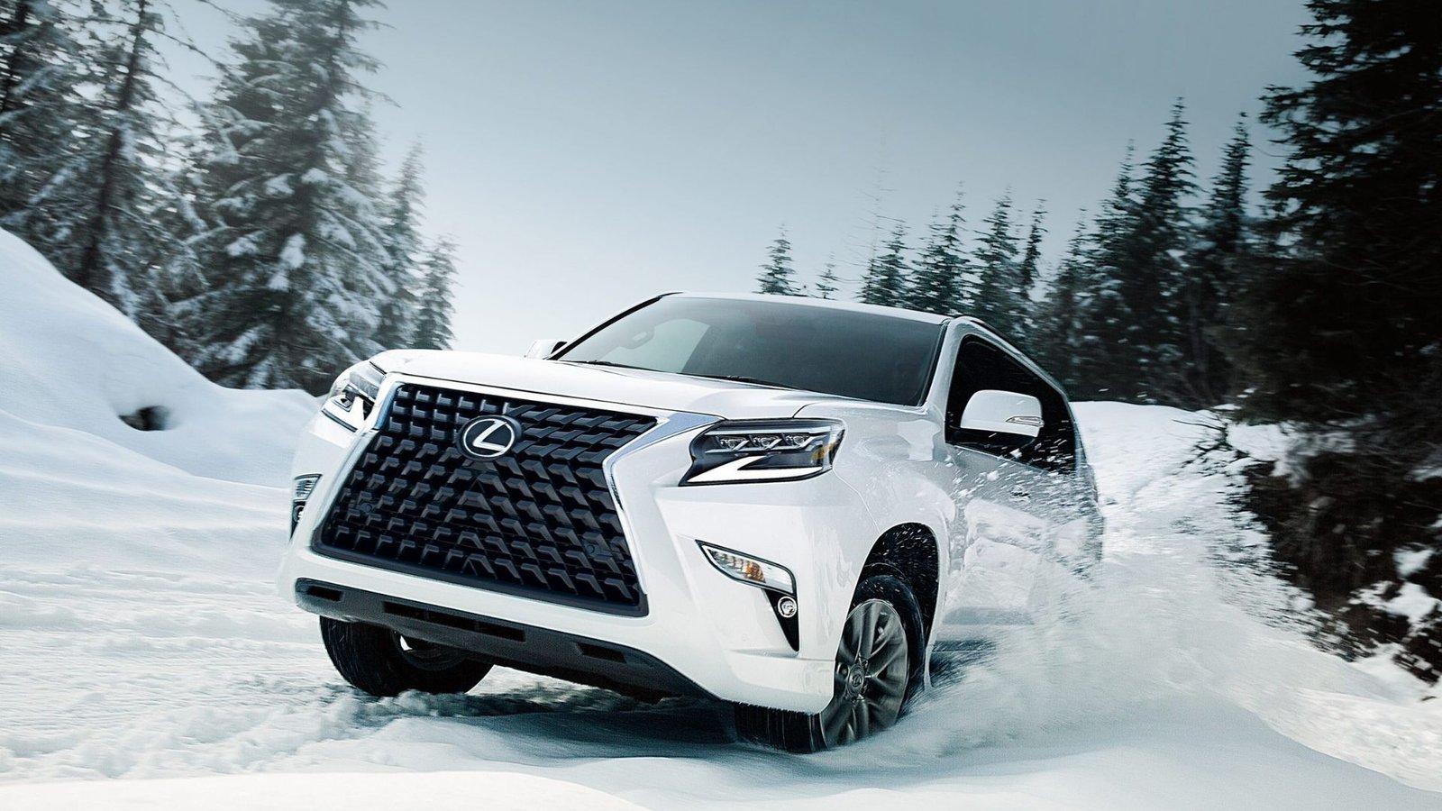 Une Lexus GX blanche 2022 traversant la neige dans une zone boisée.