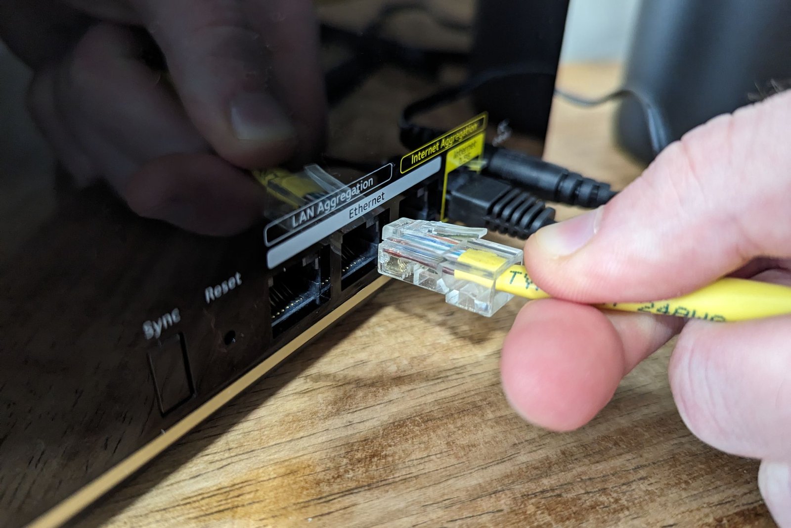 Personne branchant un câble Ethernet dans un port sur le système WiFi 6E à maillage Tri-Band Nighthawk MK93S NightGear.