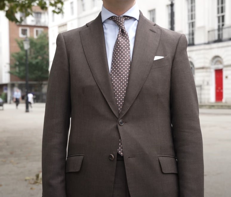 Gros plan de Jonas Froelich Hiltner's Brown Fabriqué sur mesure, avec une chemise de robe blanche, une cravate à motifs et un carré de poche