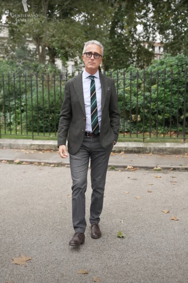 Luca Farullin de Florence, en Italie, marchant à Londres dans un look masculin classique avec un blazer en laine verte, une cravate rayée et un pantalon gris