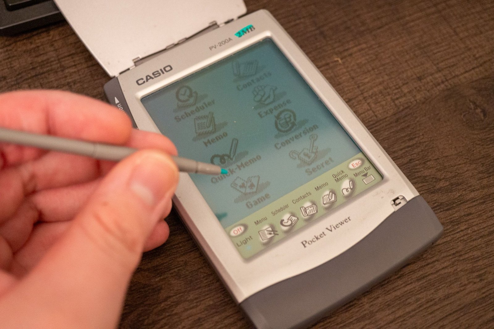 Personne utilisant un stylet sur un vieux PDA Viewer Casio Pocket.