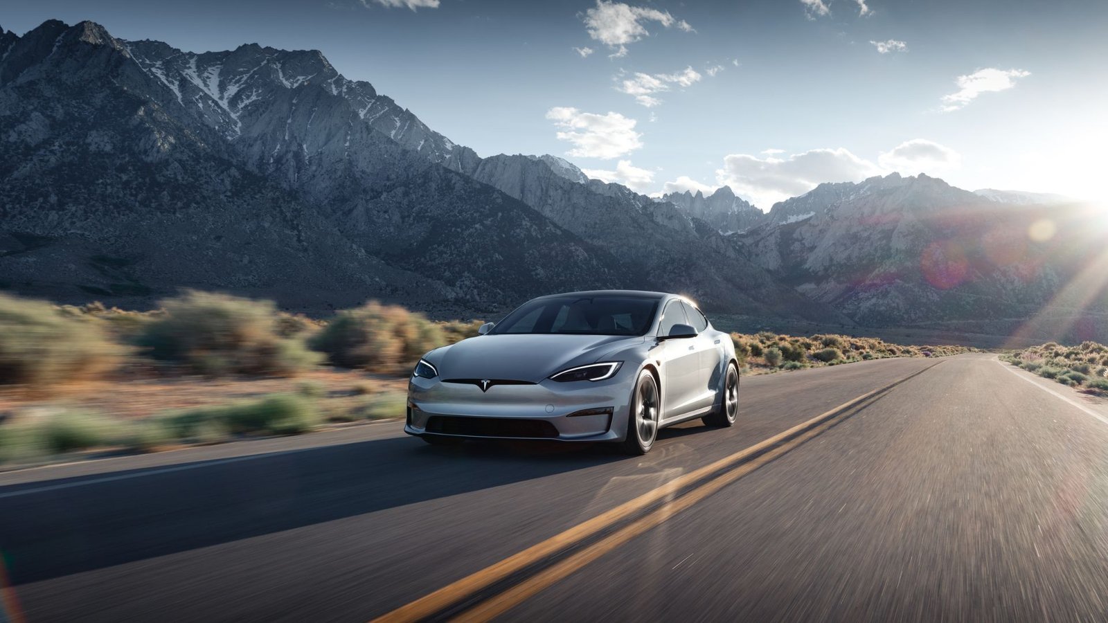 Vue de trois quarts avant d'une Tesla Model S qui conduit sur une route de campagne les montagnes.