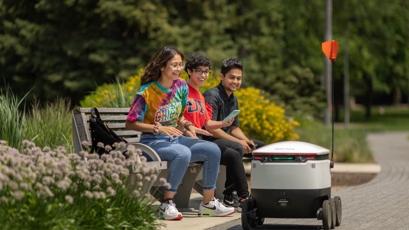 Un robot de trottoir passant devant un groupe d'adolescents