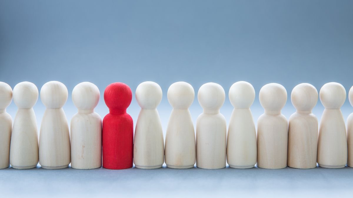 Une rangée de figurines humaines avec un rouge coloré pour se démarquer parmi les autres.