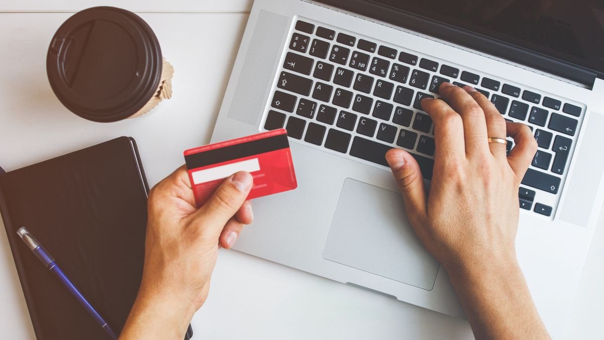 Les mains de la personne tenant une carte de crédit et tapant sur un clavier d'ordinateur portable.