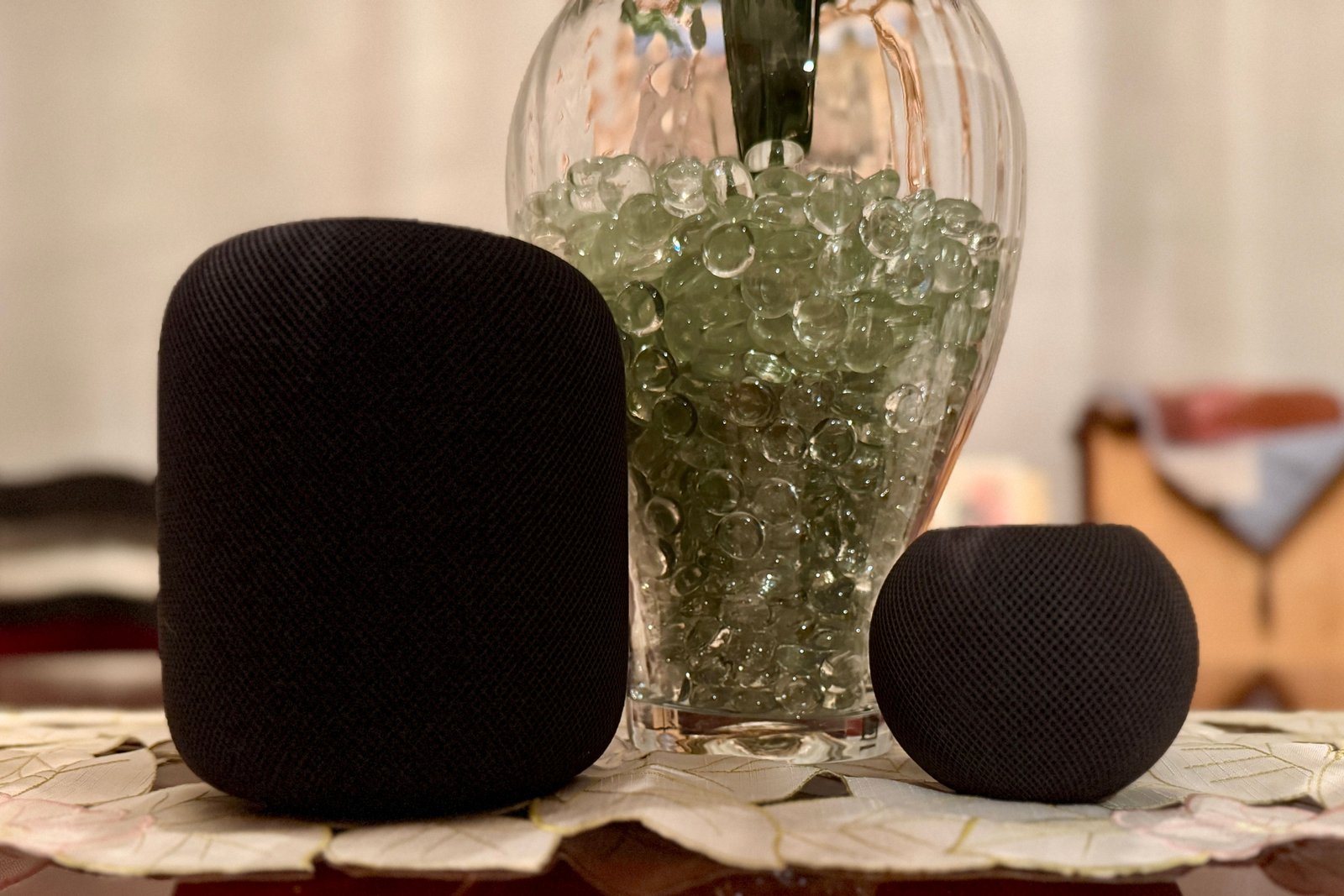 Deux homepods noirs par un vase rempli de perles.