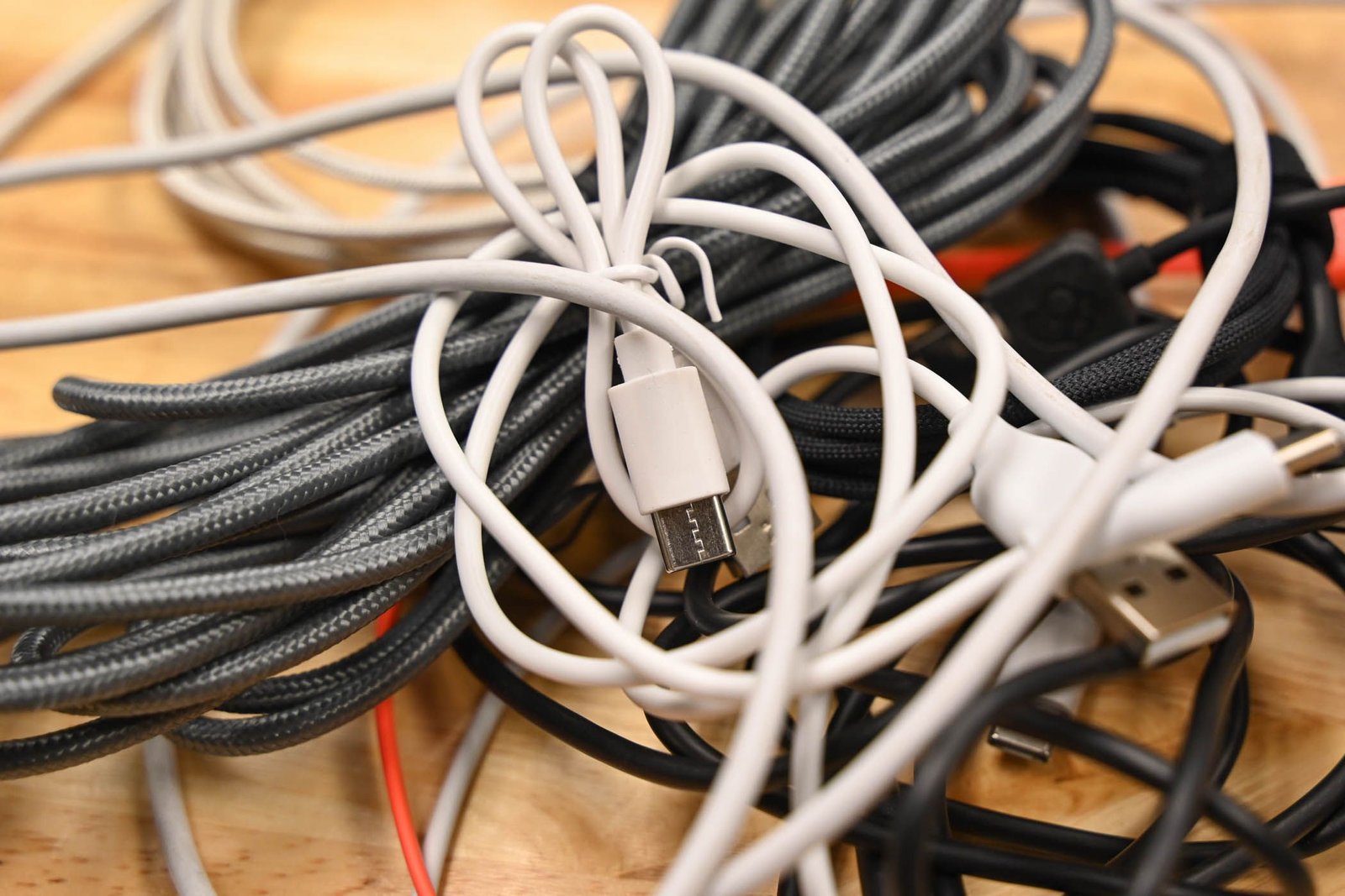 Un tas de câbles USB sur une surface en bois.