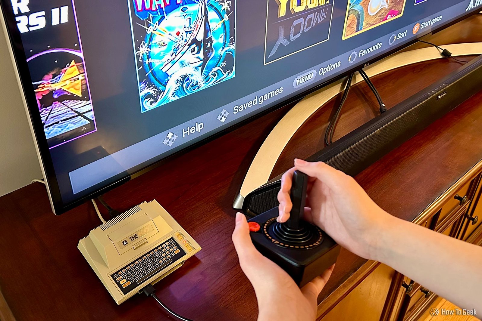 The400 Mini par une télévision avec des mains tenant le joystick