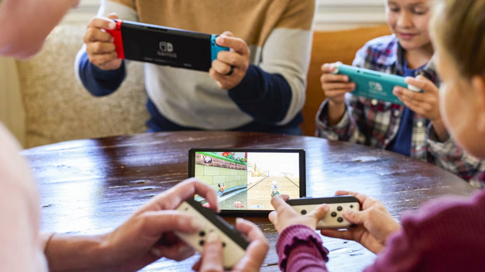 Une famille s'est rassemblée autour d'un commutateur Nintendo tenant des consoles de commutation supplémentaires.