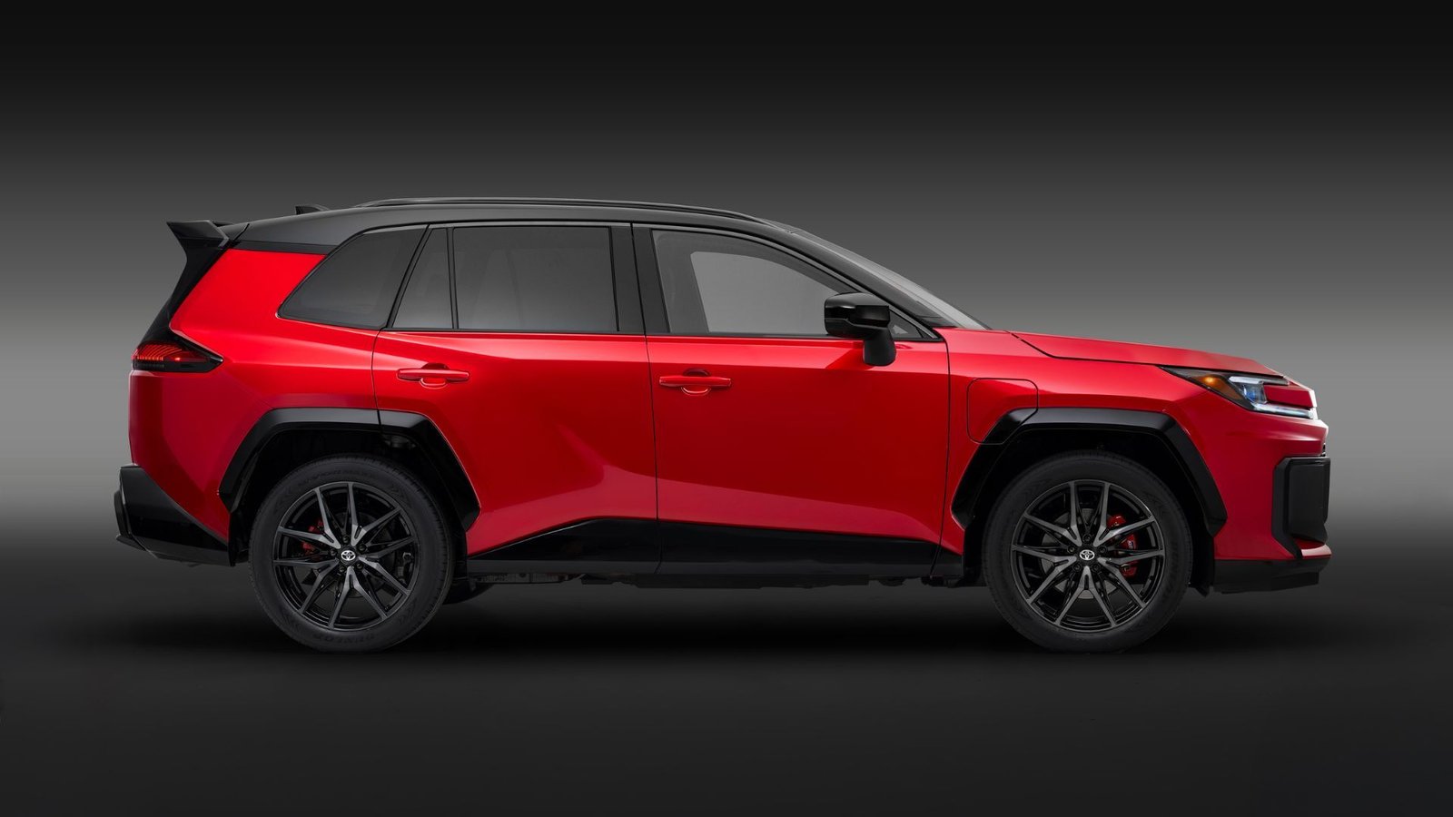 Profil latéral statique THAT D'UN SPORT TOYOTA RAV4 PHEV GR GR GR 2026 RED 2026 dans un studio avec une toile de fond noire et grise.