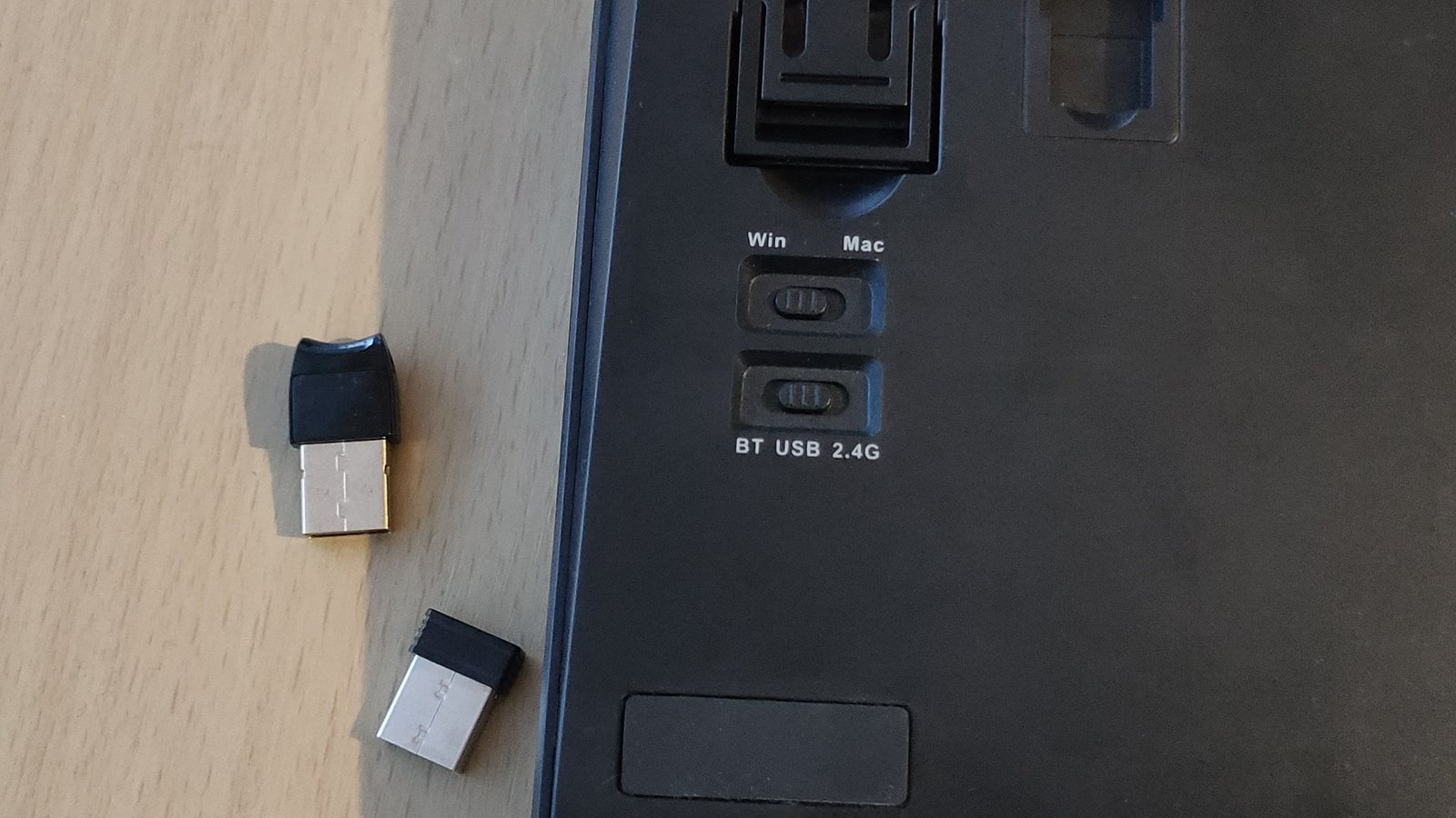 Un interrupteur Bluetooth / USB / 2,4 g à l'arrière d'un clavier avec un dongle USB et 2,4 GHz.
