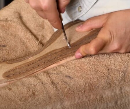Une paire de mains utilise un AWL incurvé pour coudre les couches d'une semelle de chaussure en cuir. Un processus d'allumage à la main.