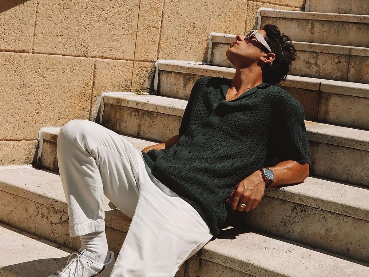 Modèle masculin dans une chemise tricotée noire et un pantalon blanc