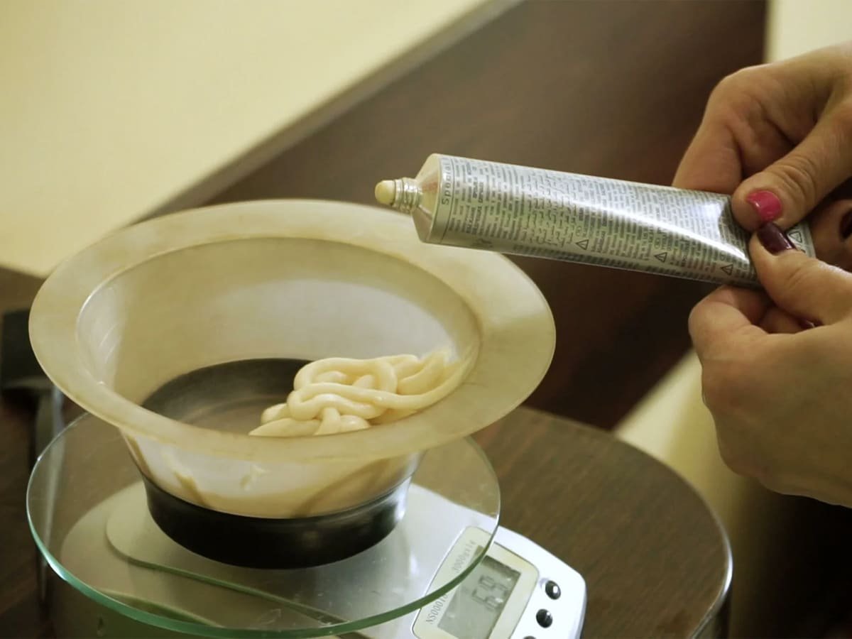 Coiffeur mélangeant des colorants dans un bol en plastique pour la coloration des cheveux