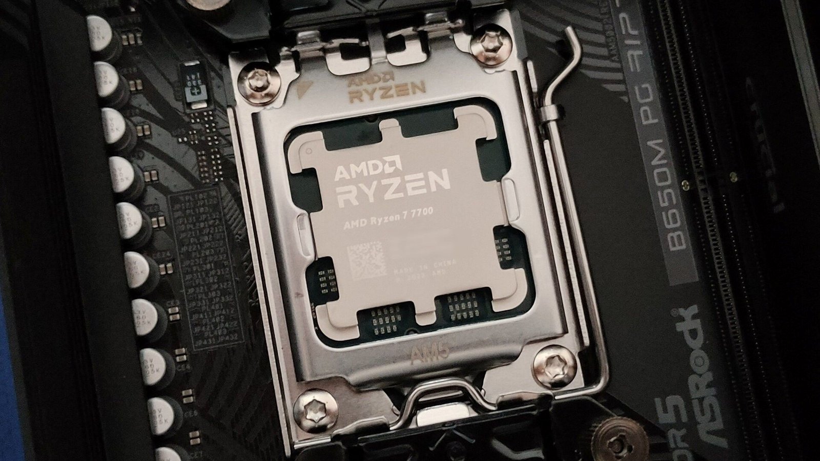 Une photo rapprochée du processeur AMD Ryzen 7 7700 dans la douille AM5 et la carte mère ASROCK B650M PG Riptide.